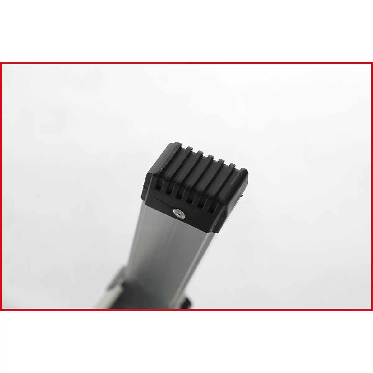 Detailaufnahme eines Leiterfußes mit schwarzem Gummipuffer und geriffelter Oberfläche. Die Leiter selbst ist aus Aluminium.